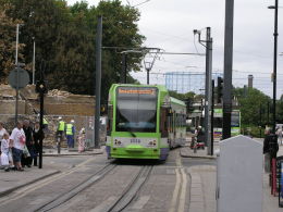 A Croydon tram passes the site of last week's riots: the building on the left is being demolished after it was gutted in the disturbances